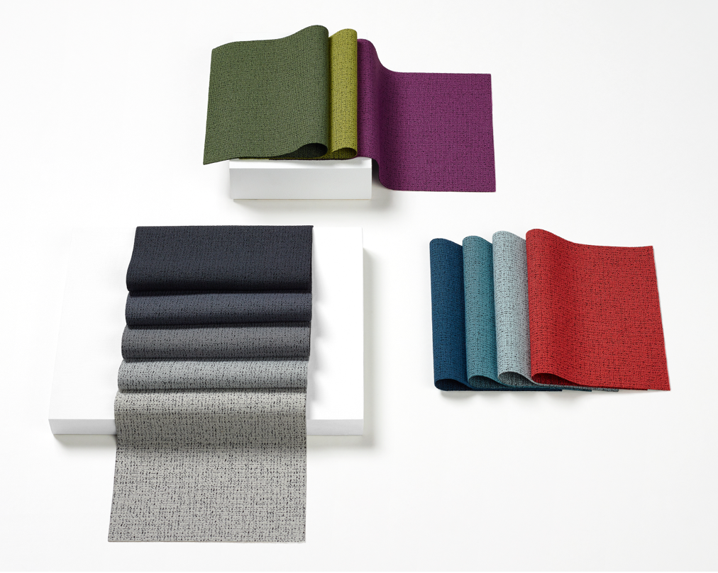 An image of Scatter fabric swatches on a white worksurface. Colors range from vibrant to neutral and include black, grey, green, purple, blue, and red.