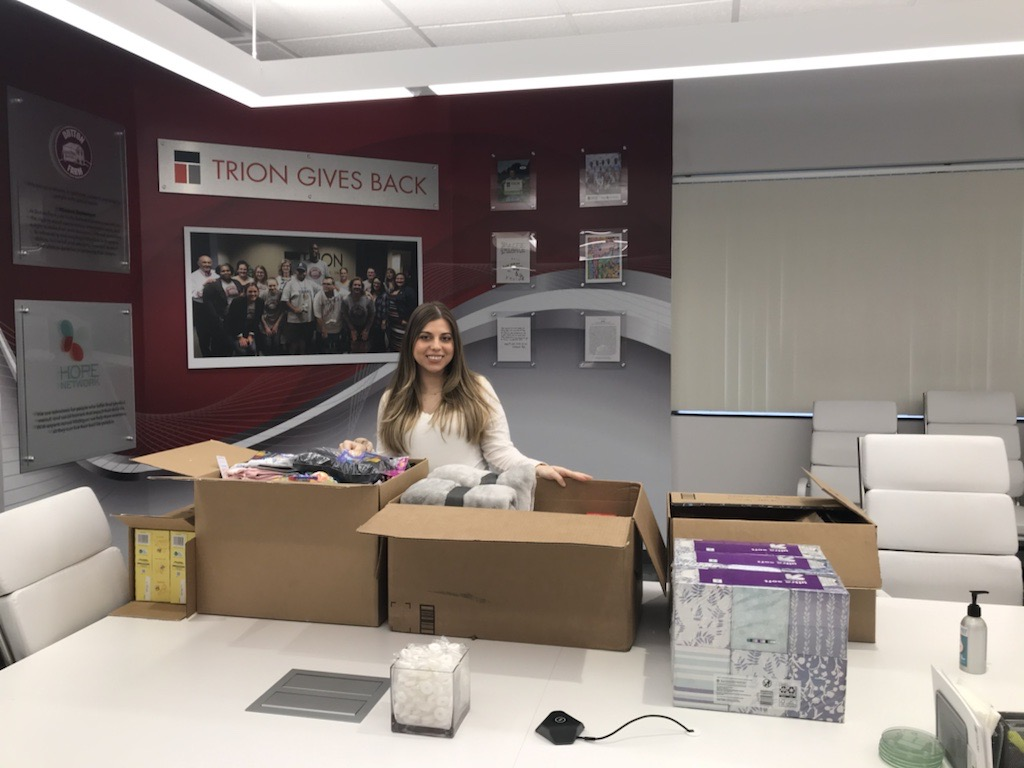 An image of a woman in the Trion Solutions office packing boxes of donations.