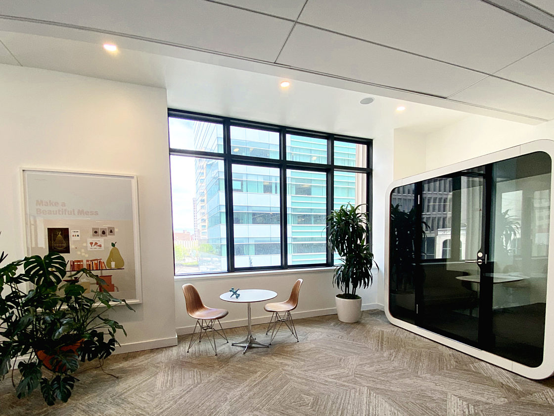 A white Framery Q on the second floor of our headquarters next to two wood Eames Side Chairs and a white Eames table.
