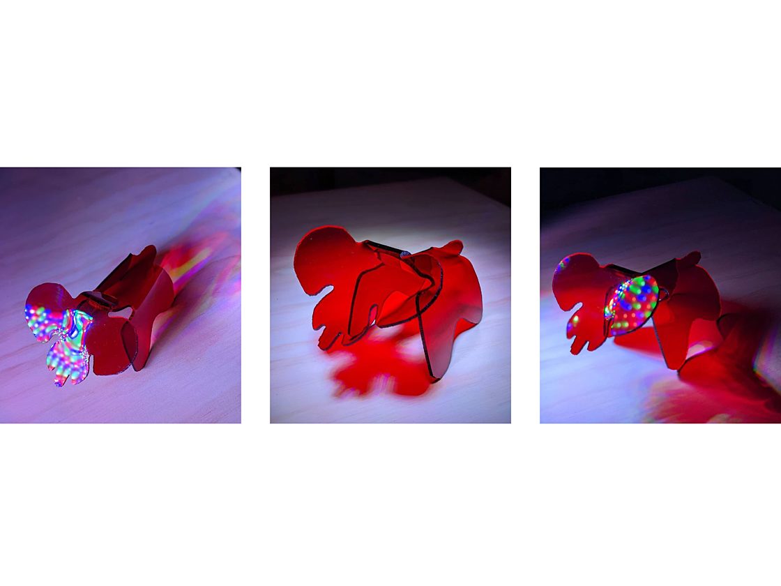 Three images of a three dimensional translucent red acrylic elephant from different angles with multicolored lights reflecting off it.