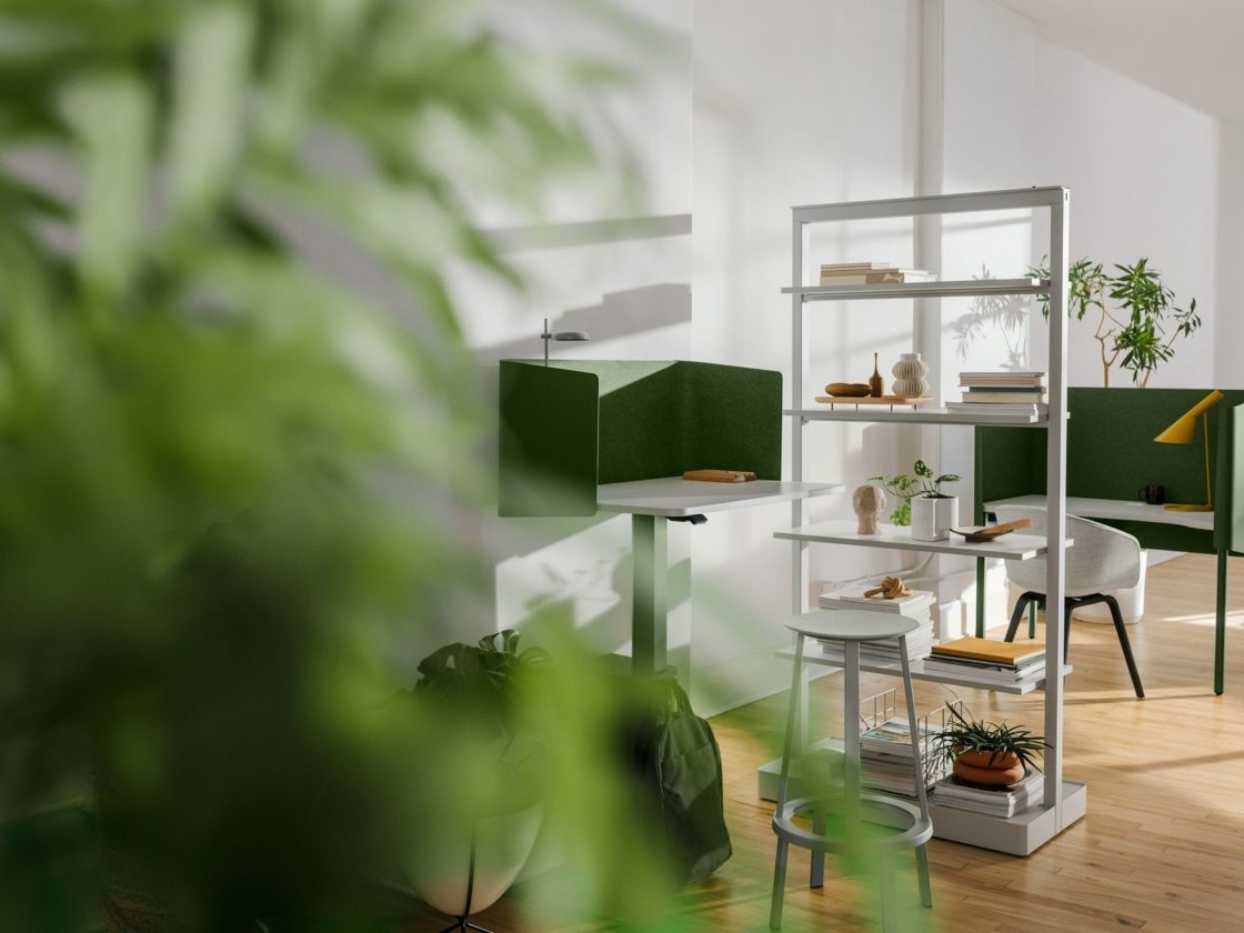 Plants in the foreground with an tall grey Agile Wall with storage shelves dividing a workspace with a OE1 Nook and a workspace with a OE1 Micropack.
