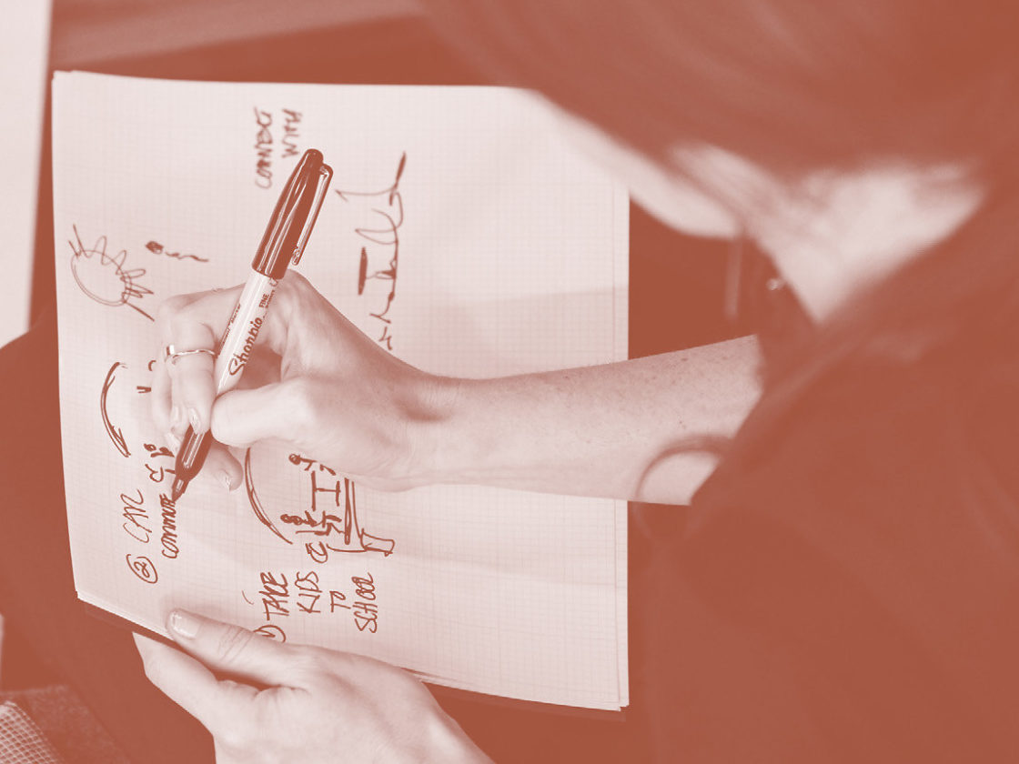A photo of a woman drawing a diagram on paper.