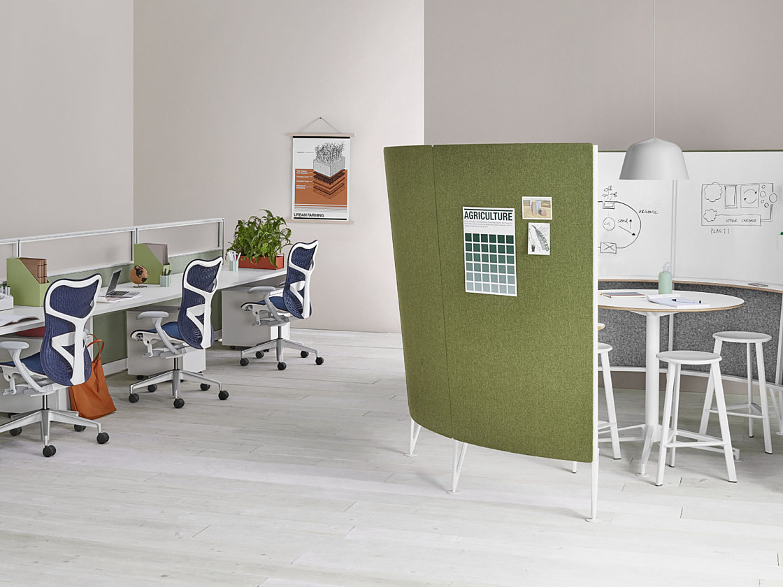 A semi-circular Prospect Creative Space with a green tackable fabric outside and a whiteboard inside with a white table and white stools inside.