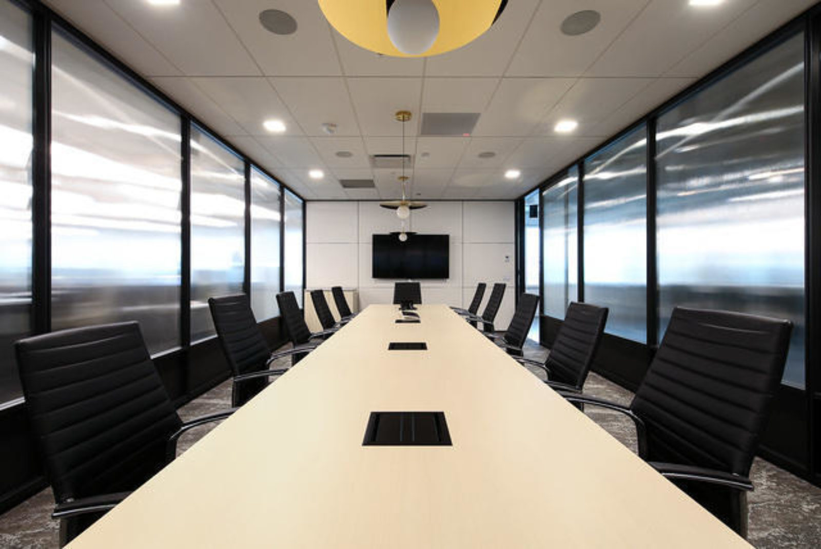 A conference room lined two sides with glass and metal walls and doors.