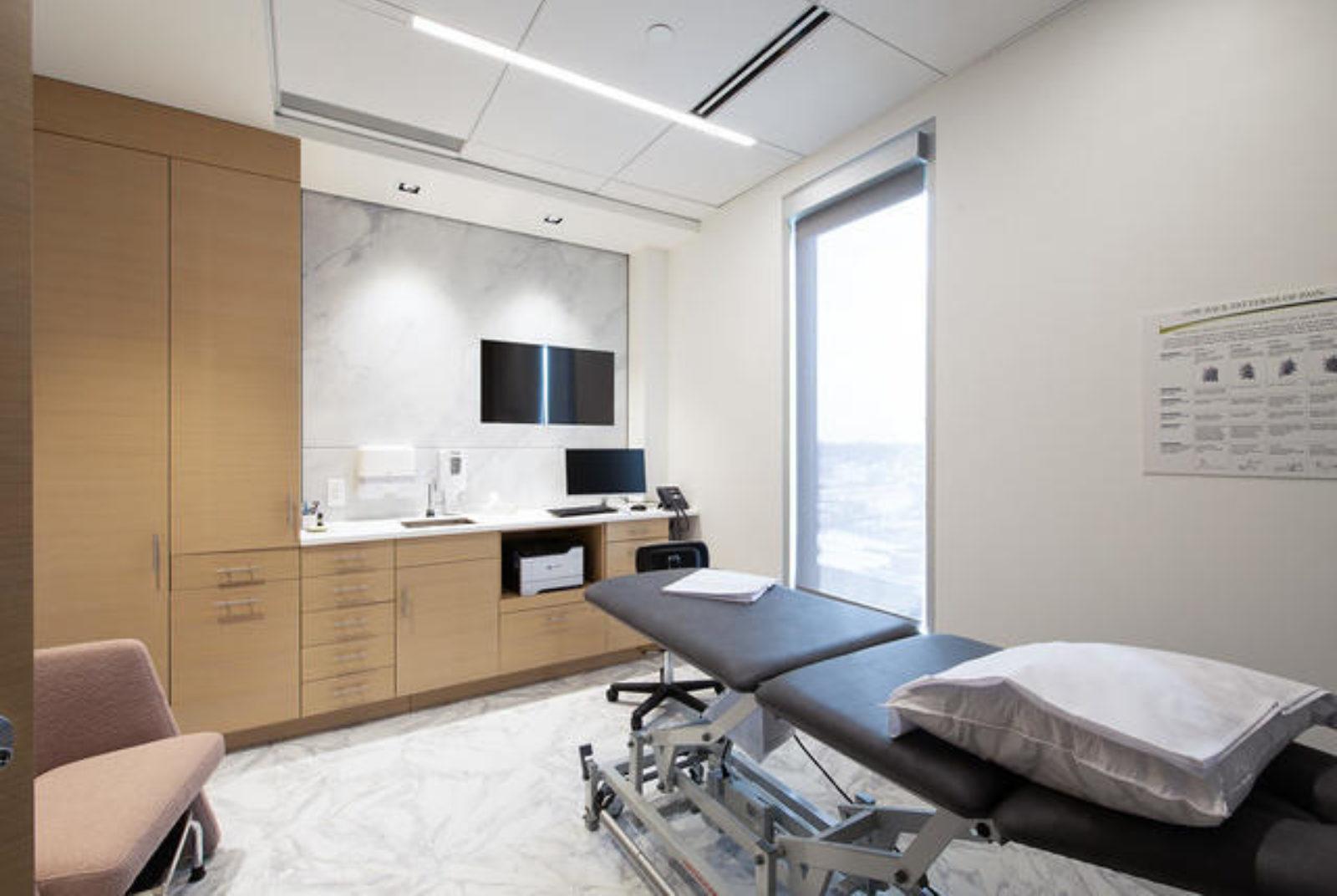 The interior of a patient room with a hospital bed and wood prefabricated casework.