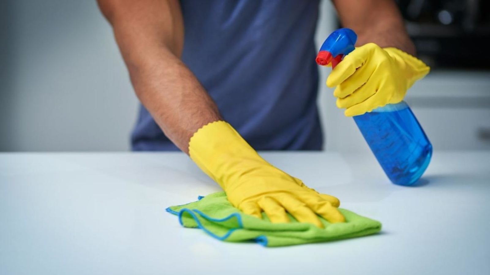 A person with gloves cleaning a surface.