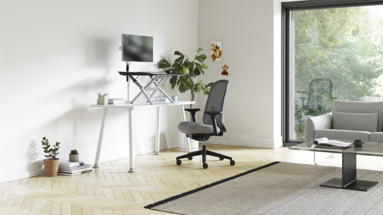 A home office with a Monto Sit-Stand Riser on a Memo Desk with a Verus Chair in front of it.