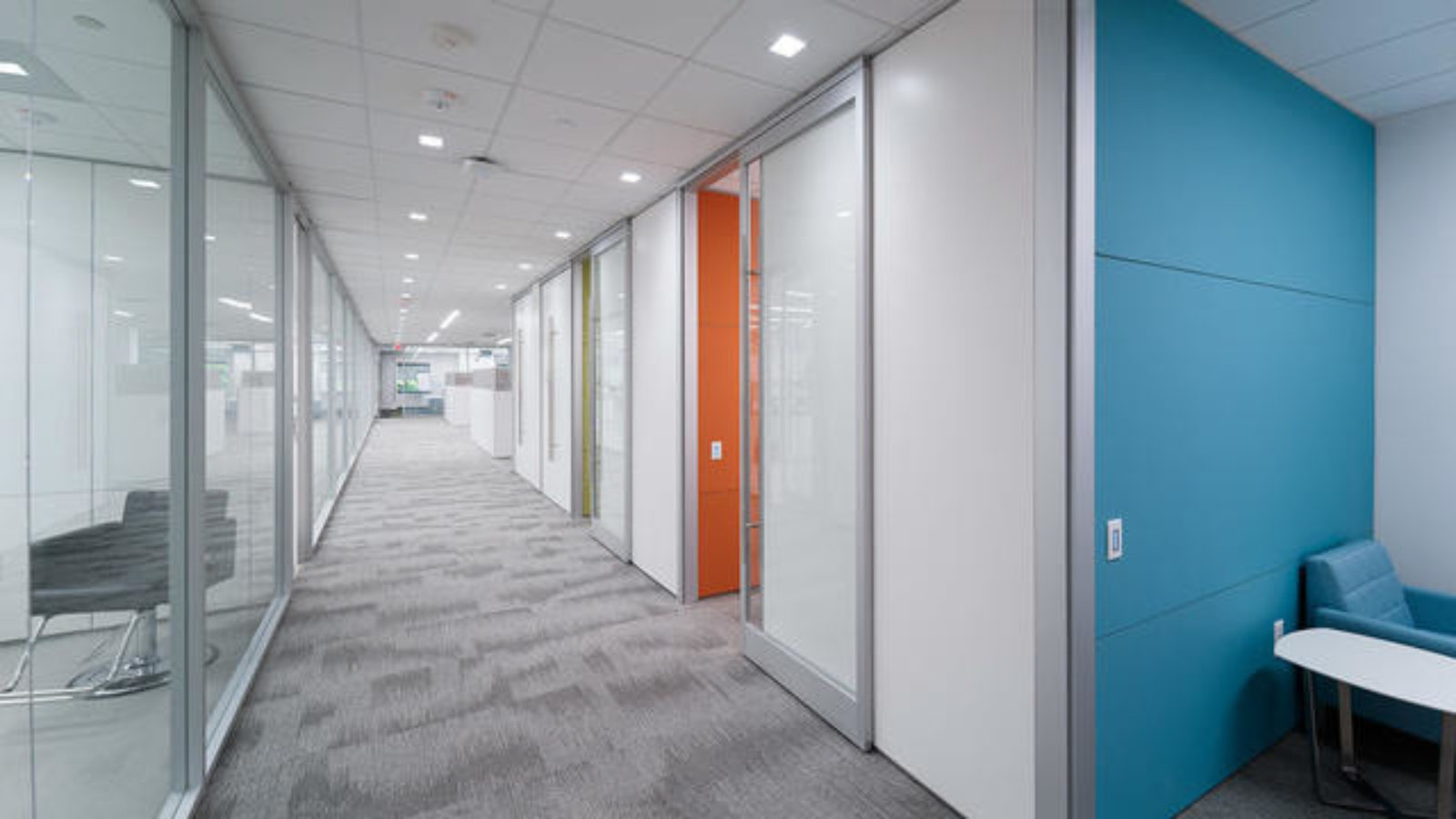 A hallway with clear and colored glass and metal prefabricated walls.