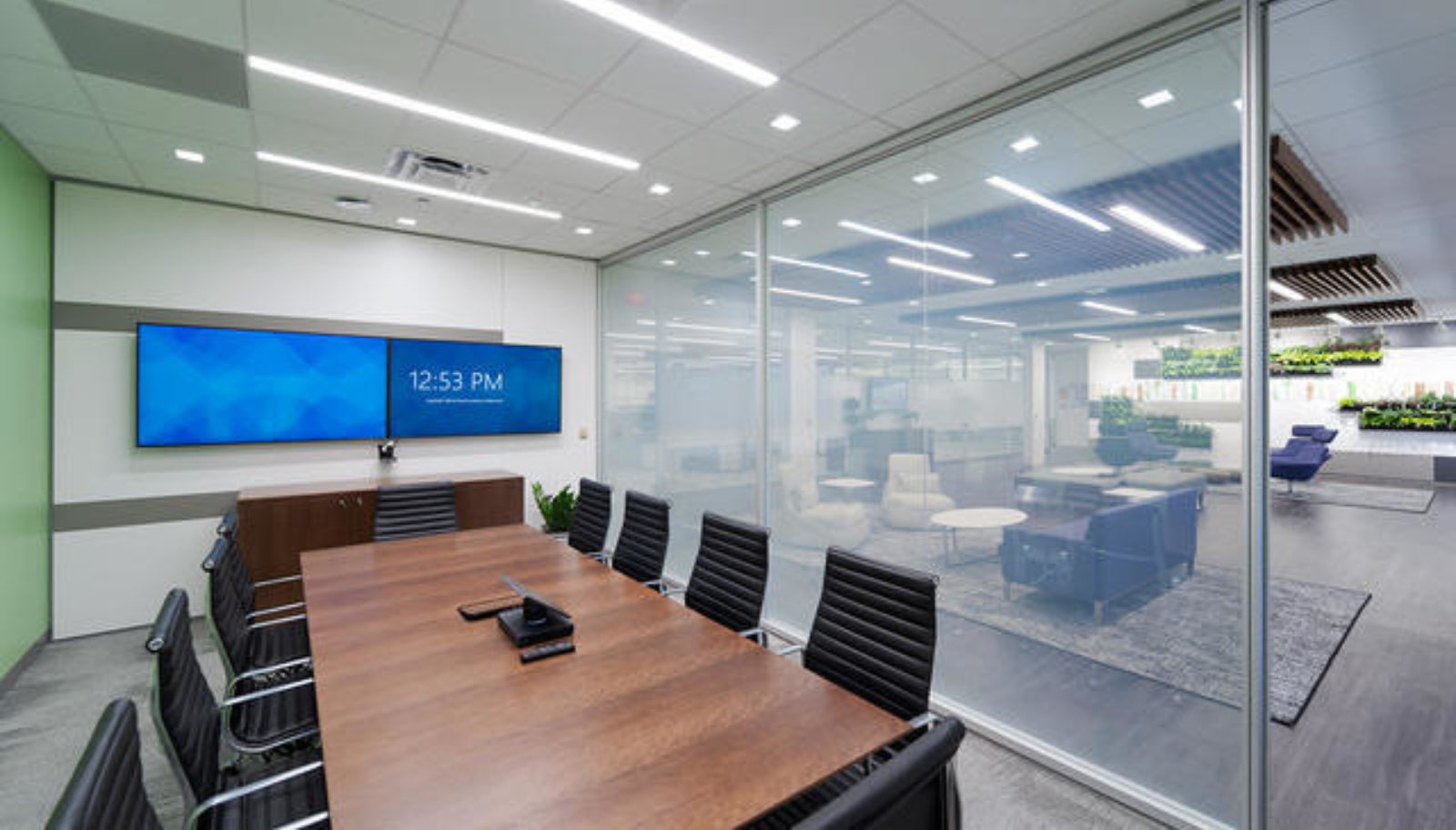 A meeting room with a DIRTT glass partition wall separating it from a lobby.