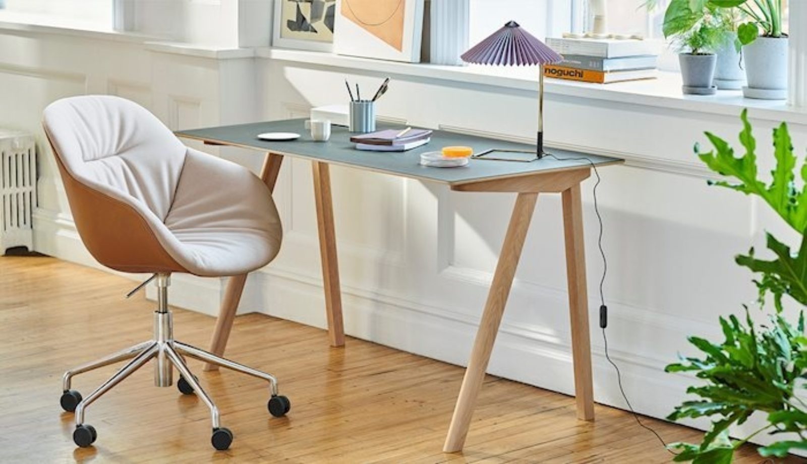 A home office with a chair, desk, and lamp from HAY.