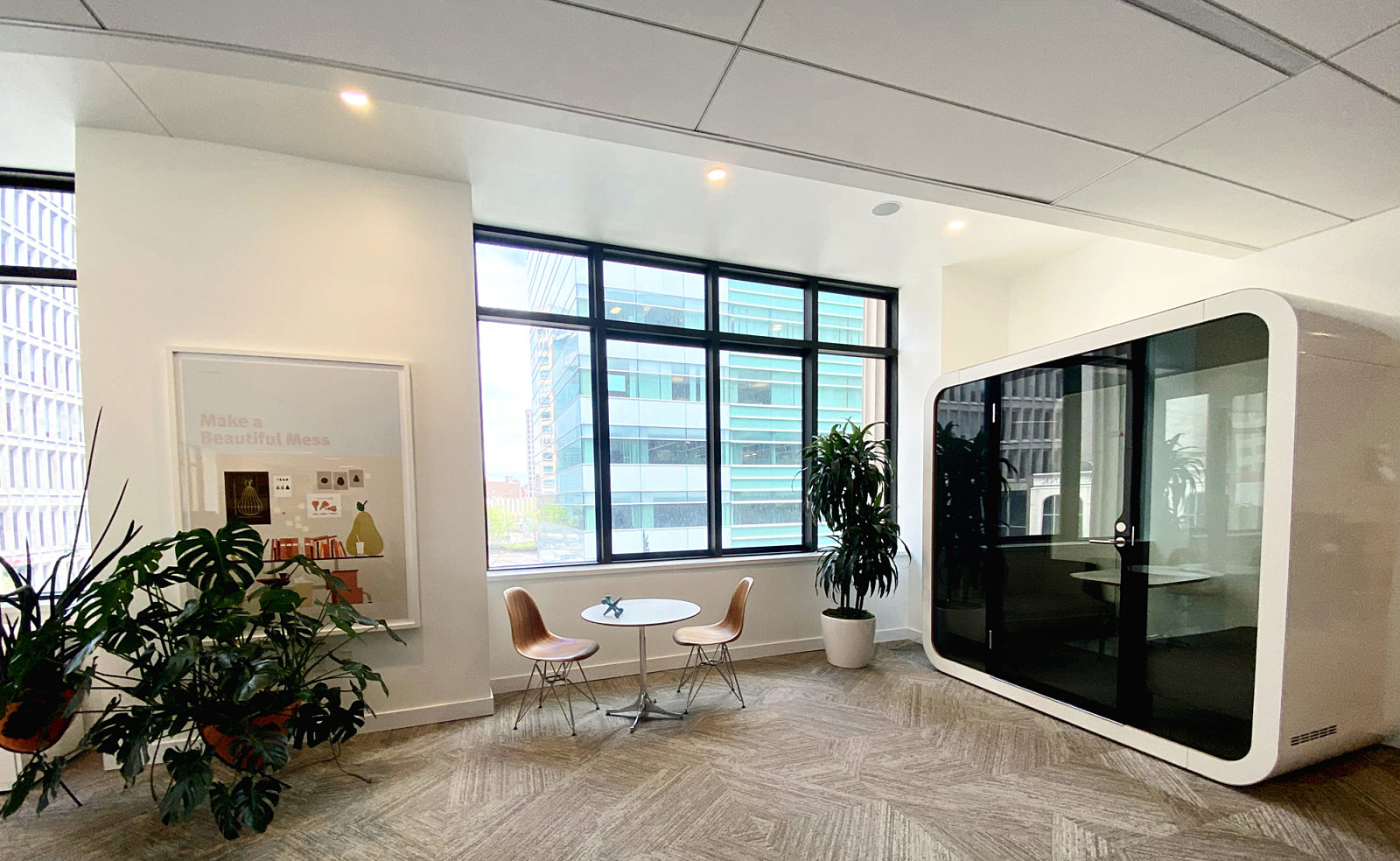A white Framery Q on the second floor of our headquarters next to two wood Eames Side Chairs and a white Eames table.