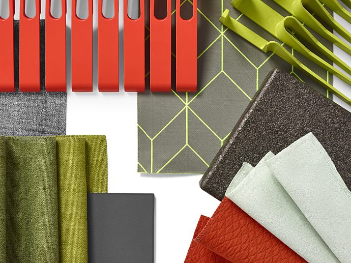A swatch board with grey, green, and burnt orange fabrics and clips.