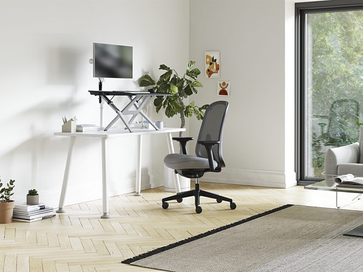 A home office with a Monto Sit-Stand Riser on a Memo Desk with a Verus Chair in front of it.